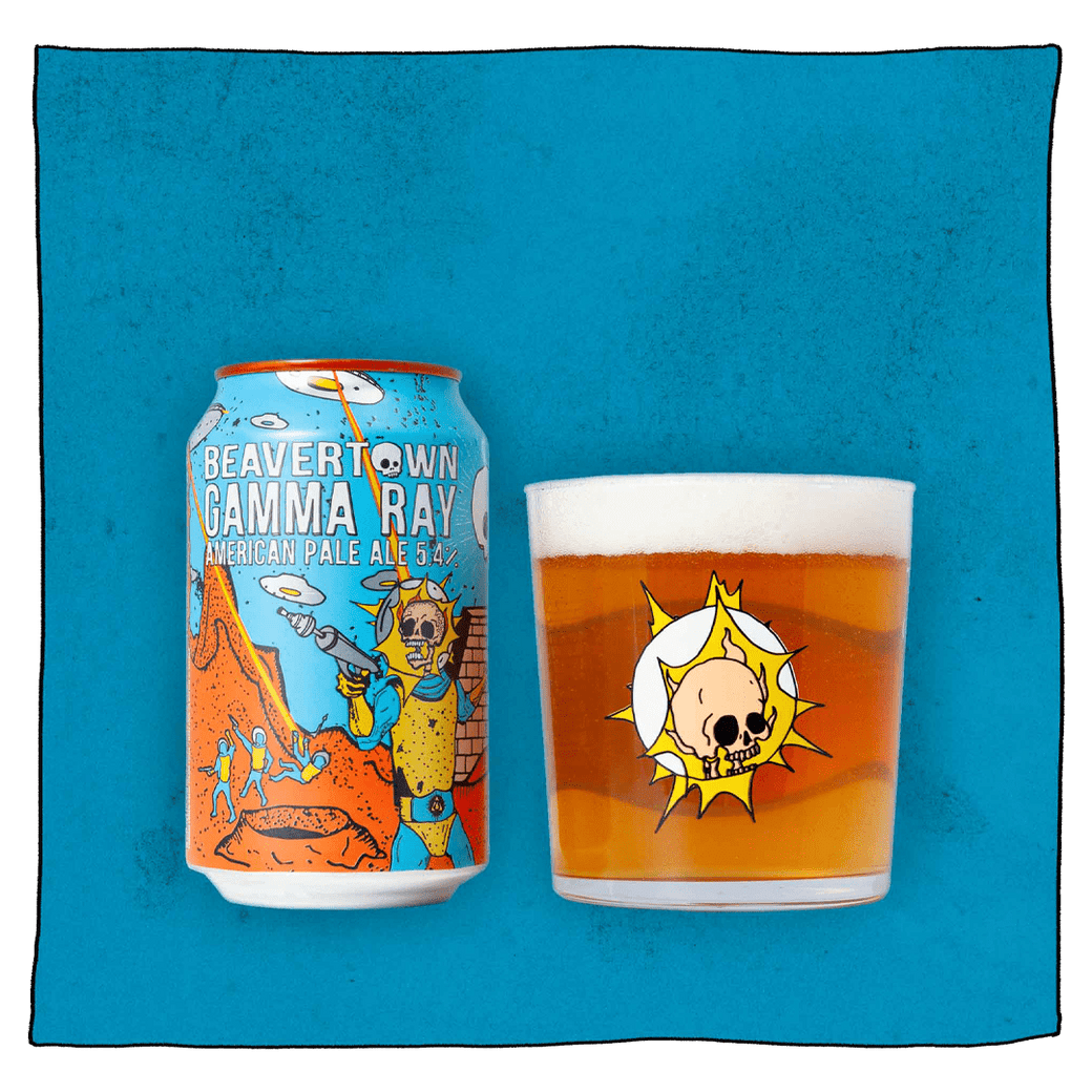 Beavertown Brewery Gamma Ray American Pale Ale Can and Beavertown Gamma Ray Tumbler glass filled with beer in front of a blue background. Beer glass is clear glass that has a salmon pink skull inside a white globe with yellow flashes. Gamma Ray American Pale Ale can is blue, orange and yellow and has a yellow and blue astronaut skeleton with a grey ray gun in the foreground and orange craters, grey UFOs and other yellow and blue astronauts in the background.
