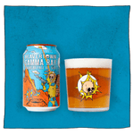 Beavertown Brewery Gamma Ray American Pale Ale Can and Beavertown Gamma Ray Tumbler glass filled with beer in front of a blue background. Beer glass is clear glass that has a salmon pink skull inside a white globe with yellow flashes. Gamma Ray American Pale Ale can is blue, orange and yellow and has a yellow and blue astronaut skeleton with a grey ray gun in the foreground and orange craters, grey UFOs and other yellow and blue astronauts in the background.