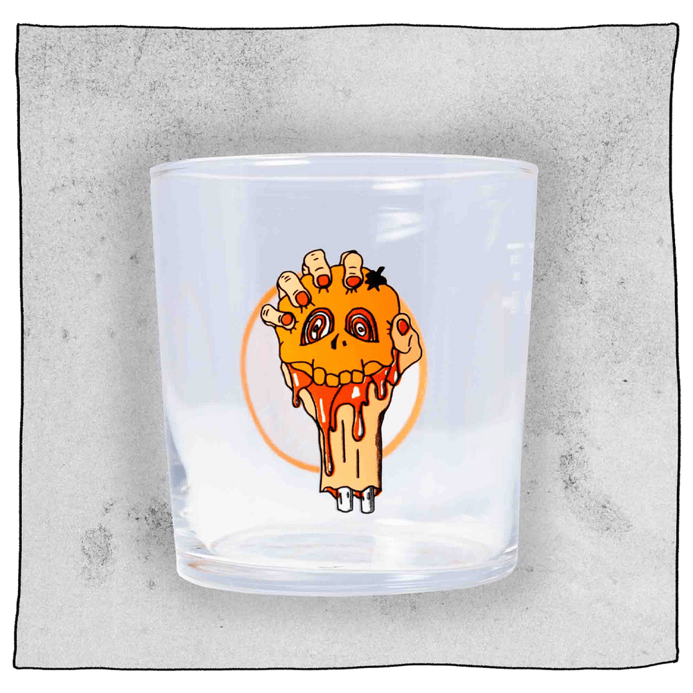 Beavertown Blood E'll Half pint glass. Blood E'll half pint glass is empty and contains a logo of a bloody severed arm with orange fingernails clenching a small orange skull. Grey background.