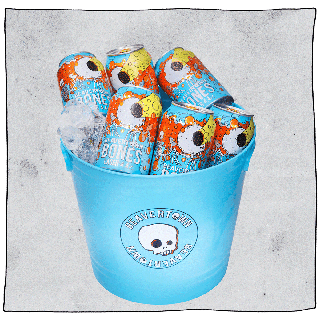 Beavertown Bones Lager & Ice Bucket Beer Bundle. Blue bucket with white skull Beavertown logo. Bucket contains 6 Bones lagers and some ice in front of a grey background.