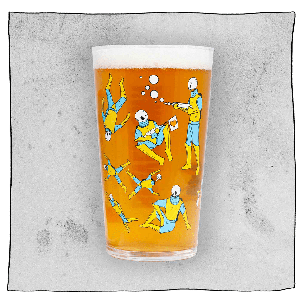 Beavertown Gamma Ray Pint Glass. Glass filled with beer and has many Gamma Ray men scattered around the glass. Grey background.