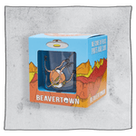 Beavertown Nanobot tumbler glass inside an orange and blue cubed box in front of a grey background. Box has artwork depicting a white UFO in an orange, yellow and red canyon with a blue sky. Bones tumbler glass is visible in middle of box and is clear with a nanobot logo. Grey background.