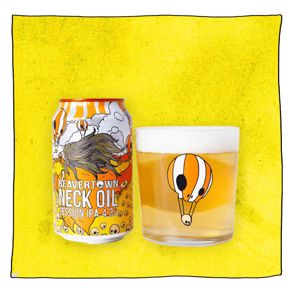 Beavertown Brewery Neck Oil IPA and Beavertown Neck Oil Tumbler glass filled with beer in front of a yellow background. Beer glass is a clear glass that has an orange and white skull themed hot air balloon in the centre.