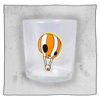 Empty Neck Oil Tumbler glass in front of a light grey background. Glass is clear with an orange and white skull hot air balloon.