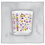 Empty Psychedelic tumbler glass in front of a grey background. Glass is clear with colourful skulls and bones scattered all around the glass.