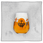 Tempus Tumbler glass filled with beer in front a grey background. Glass has orange and black  dead tree Tempus logo.